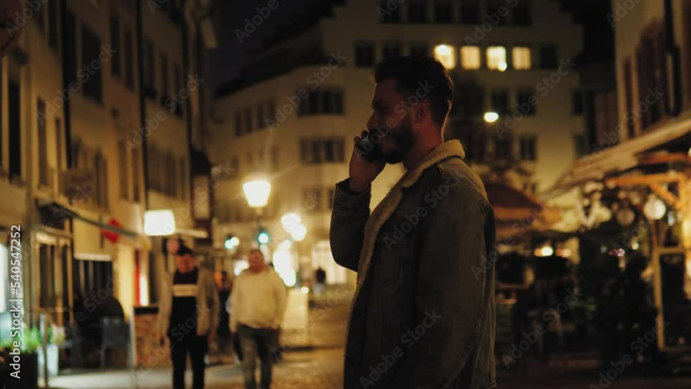 Serious man standing in the middle of the road on the street at night or evening and calling, talking on phone. Cell phone, communication online. Handsome male using phone for call in darkness Serious man standing in the middle of the road on the street at night or evening and calling, talking on phone. Cell phone, communication online. Handsome male using phone for call in darkness