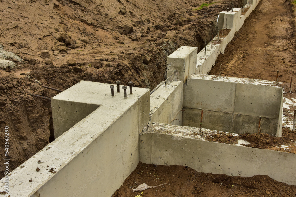 Concrete footings and foundation with anchor bolts ready for further construction. Stock Photo