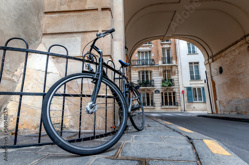 Photography An old bicycle parked on a street in downtown Paris.