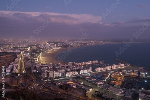  Beautiful landscape of Agadir city shore, port and city during violet summer sunset, in morocco