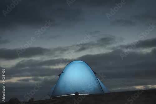 Illuminated camping tent against a beautiful sky