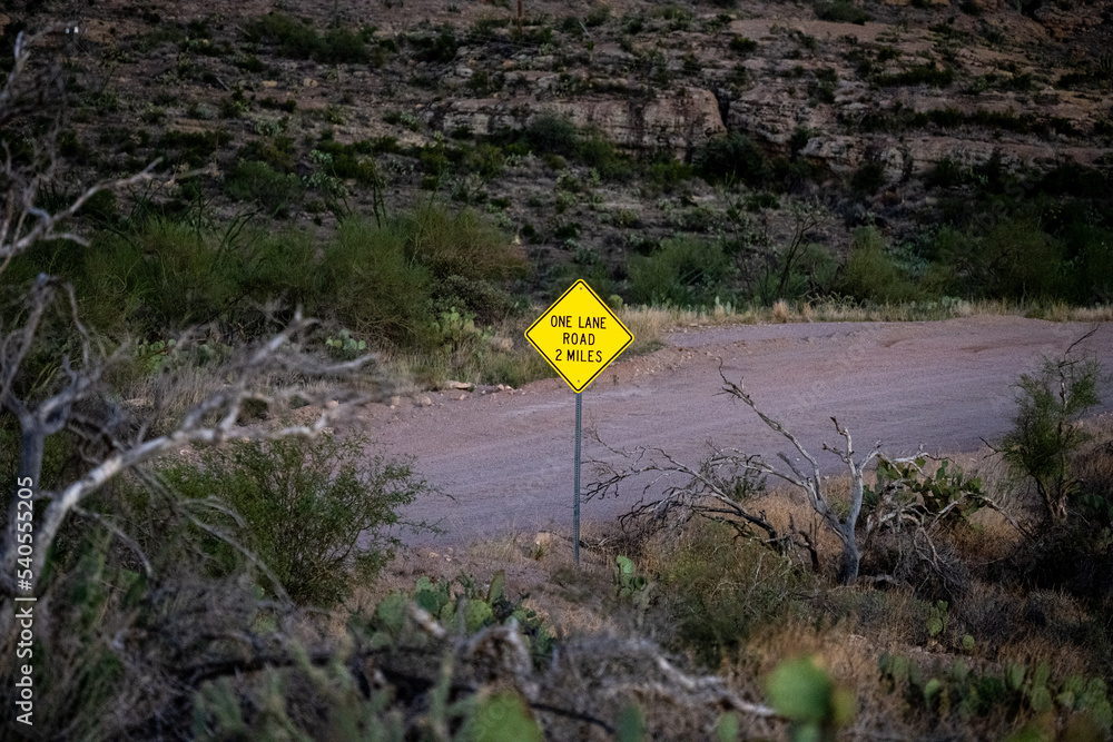 A yellow diamond sign for a one lane road 2 miles on State Route 88 Apache Trail in Arizona