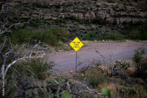 A yellow diamond sign for a one lane road 2 miles on State Route 88 Apache Trail in Arizona