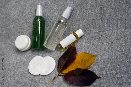 Jars with cream, shampoo and cosmetics on a background with autumn leaves