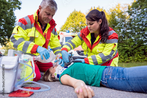 Emergency doctor ventilating injured woman after motorbike accident giving first aid photo