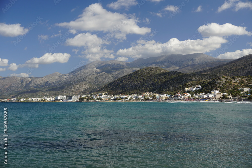 Aegean Sea in Crete. White clouds hang over the mountains. Azure water.