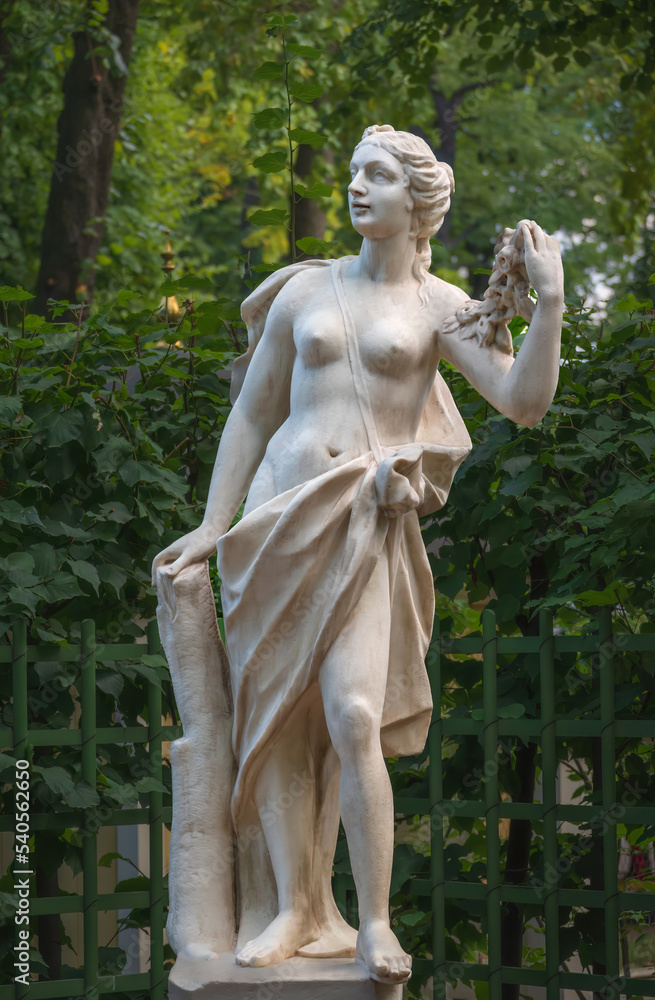 Fototapeta premium Statue of a woman with a garland of roses in Summer garden, Saint Petersburg, Russia