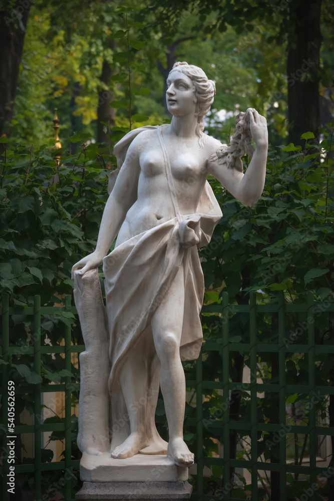 Statue of a woman with a garland of roses in Summer garden, Saint Petersburg, Russia