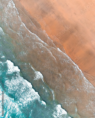 Aerial view of the waves of the beach hitting the shoreline of a beach photo