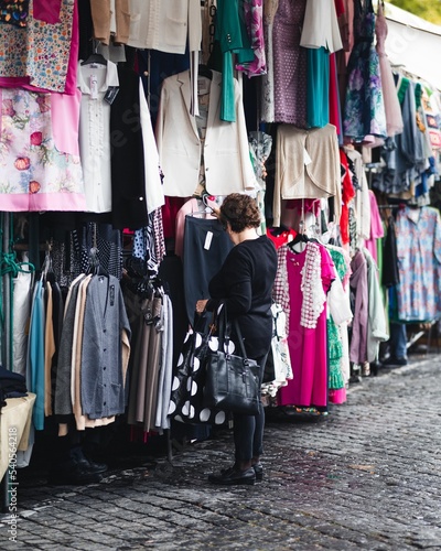 Vertical shot of a woman shopping for clothes from a street market in Barcelos, Portugal photo