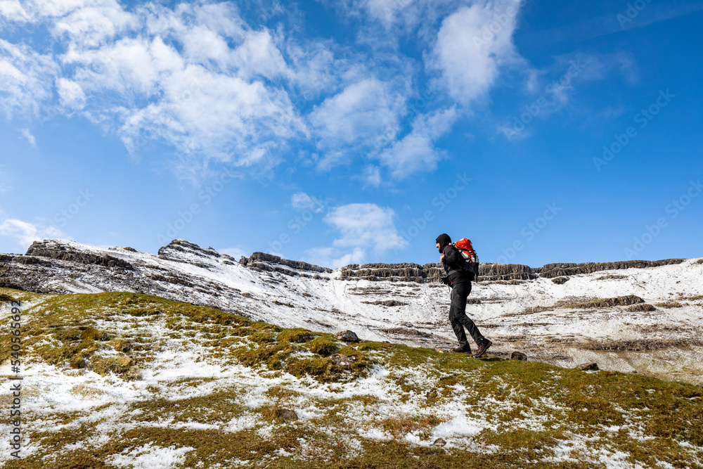 Man hiking in Scotland, Isle of Skye, with snowy mountains on background
