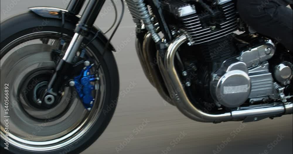 Close-up of a motorcycle riding on a road at high speed. Side view. Driving Bike on Streets. Speed Motion in Cityscape. Fast TRACKING Shot of a biker riding his custom built cafe racer through city. Close-up of a motorcycle riding on a road at high speed. Side view. Driving Bike on Streets. Speed Motion in Cityscape. Fast TRACKING Shot of a biker riding his custom built cafe racer through city.
