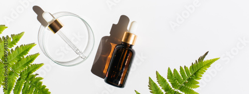 Petri dishes, cosmetic glass bottles on white background.Natural medicine, cosmetic research, bioscience, organic skin care products. Top view, flat lay. Scientific laboratory glassware. Dermatology