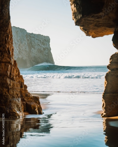Beautiful view of a beach with a surfer from a cliff during sunrise photo