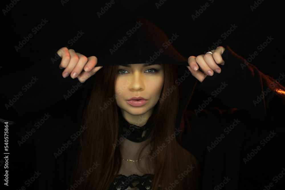 portrait of a beautiful young red-haired girl on a dark black background in the studio, with a cleavage and big breasts in black hood, hoodie portrait of a beautiful young red-haired girl on a dark black background in the studio, with a cleavage and big breasts in black hood, hoodie