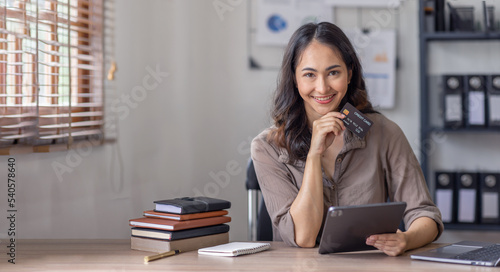 Shopping and online payment, Smilling Asian business woman using tablet and holding credit card look at the camera.