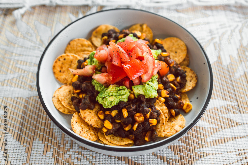healthy plant-based food, vegan mexican bean nachos with corn chips guacamole and tomato salsa