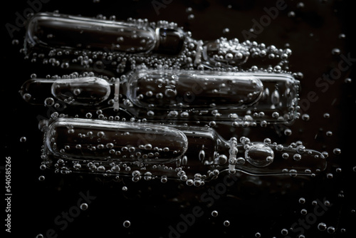 Cosmetic ampoules in bubbles in water on a black background.Cosmetics medical and care