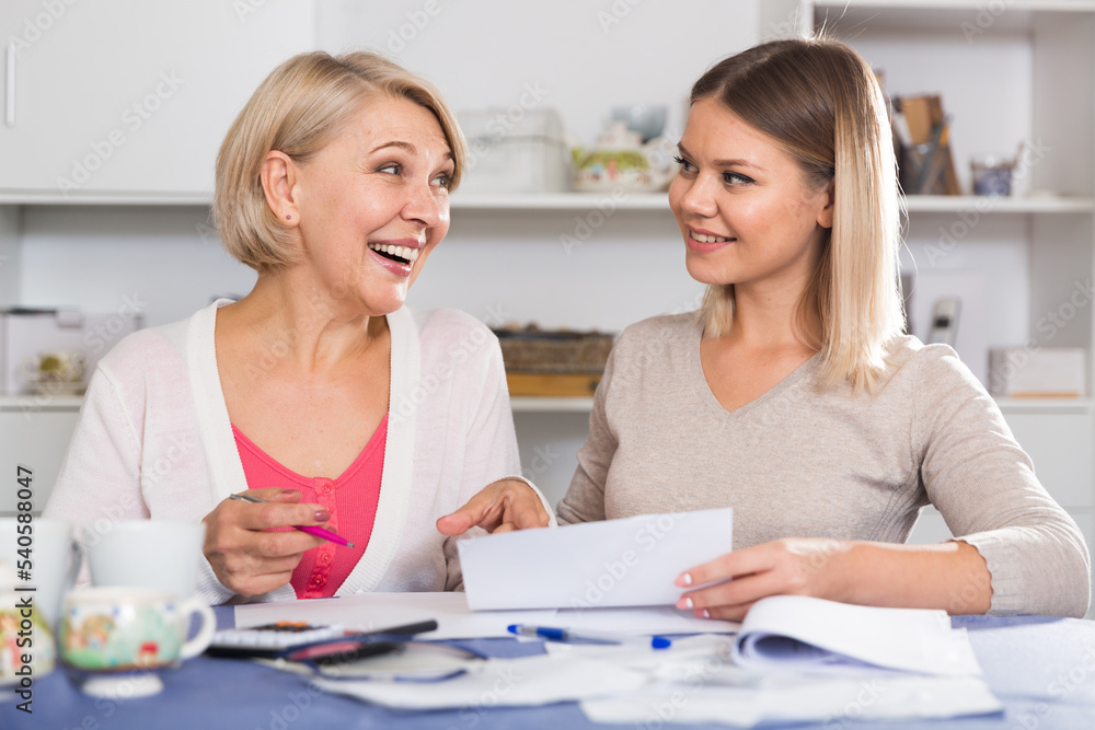 Obraz premium Grown daughter helps her mother deal with bills and taxes