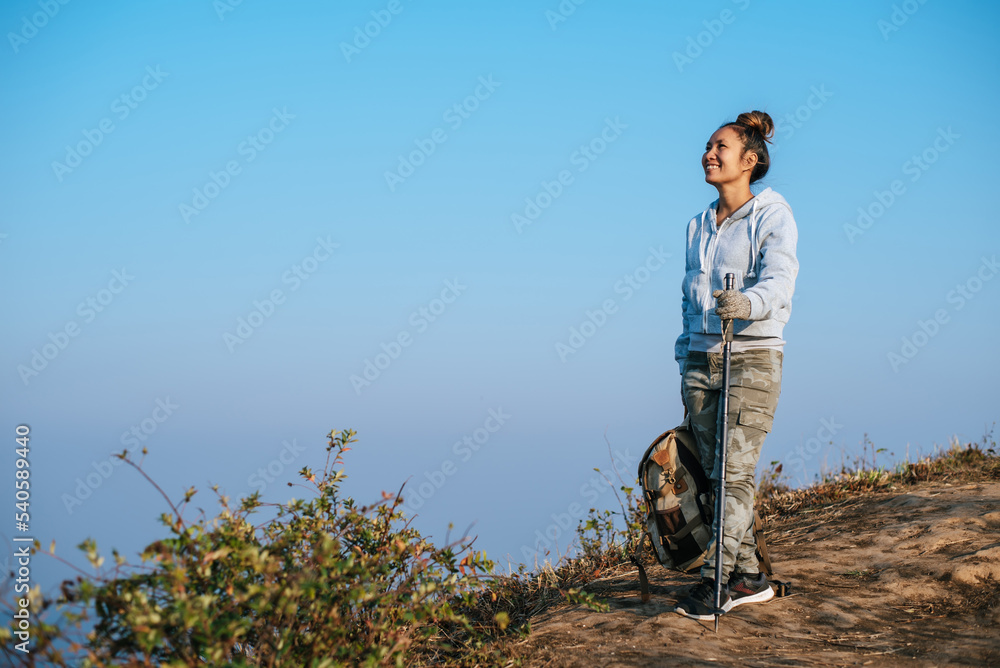 Portrait of Asian young tourist woman is hiking on the top of the mounting and looking at a beautiful landscape with copy space Portrait of Asian young tourist woman is hiking on the top of the mounting and looking at a beautiful landscape with copy space
