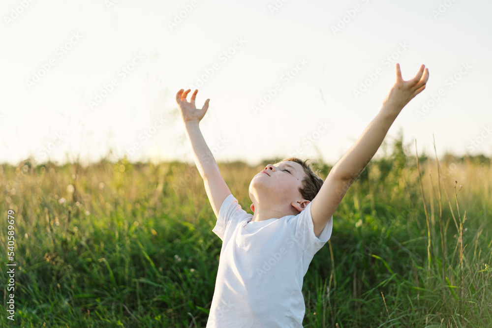 Boy closed her eyes and praying in a field at sunset. Hands folded in prayer concept for faith, spirituality and religion. Boy closed her eyes and praying in a field at sunset. Hands folded in prayer concept for faith, spirituality and religion.