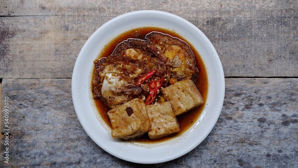 Semur telur dan tahu. Is Indonesian traditional side dish made with sunny side up and tofu cooked with soy sauce and some spices like cinnamon, coriander, pepper, garlic, shallots and chili Semur telur dan tahu. Is Indonesian traditional side dish made with sunny side up and tofu cooked with soy sauce and some spices like cinnamon, coriander, pepper, garlic, shallots and chili