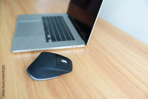 Ergonomic vertical mouse with laptop computer on adjustable desk at workplace, prevention wrist pain. De Quervain s tenosynovitis, Intersection Symptom, Carpal Tunnel or Office syndrome concept photo