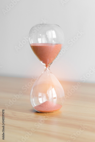 Hourglass on table, Sand flowing through the bulb of Sandglass measuring the passing time. countdown, patience, deadline, Life time and Retirement concept