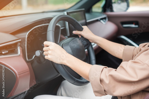 woman driver driving a car on the road, hand controlling steering wheel in electric modern automobile. Journey, trip and safety Transportation concepts