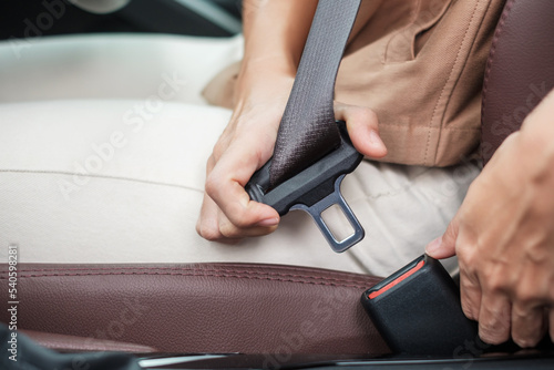 woman driver hand fastening seat belt during sitting inside a car and driving in the road. safety  trip  journey and transport concept