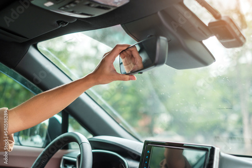 Fototapeta woman driver adjusting rear view mirror a car