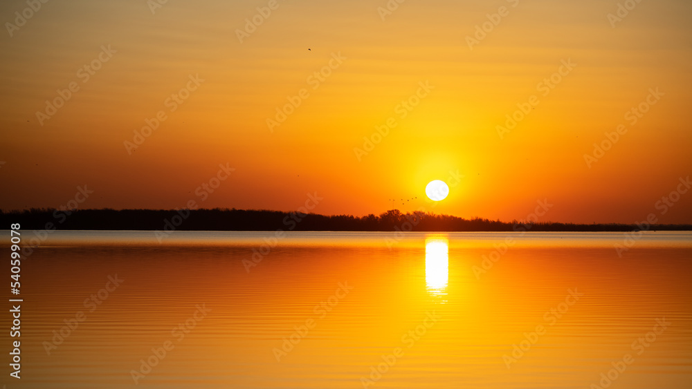 Beautiful colorful sunset with the sun over lake in Buenos Aires, Argentina. Water reflection