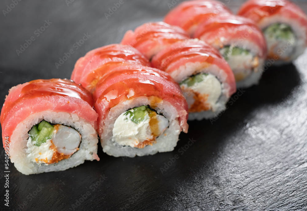 uramaki sushi roll with shrimp tiger, caviar, unagi covered by tuna on black background. Sushi menu. Japanese kitchen uramaki sushi roll with shrimp tiger, caviar, unagi covered by tuna on black background. Sushi menu. Japanese kitchen