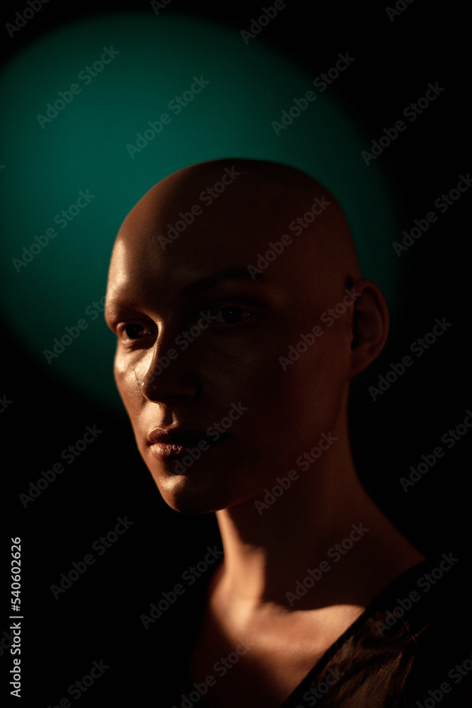 Portrait of bald young woman with blank expression against black background Portrait of bald young woman with blank expression against black background