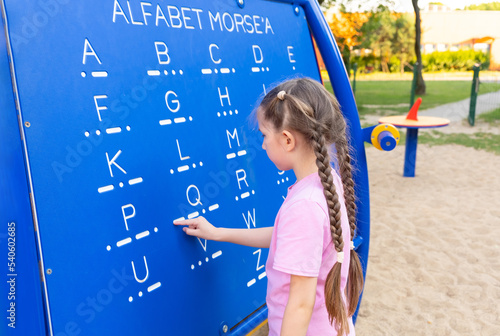 Valokuva A little girl 7-8 years old with long hair dressed in a pink T-shirt and shorts