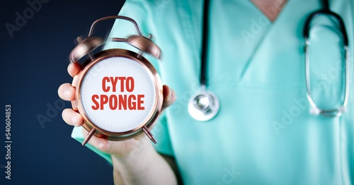 Cytosponge. Doctor shows alarm clock with medical text. Background blue. photo