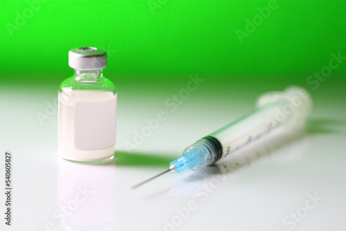 Medical vial of a neon green substance and hypodermic needle. Concept of drug addiction or toxic substance.