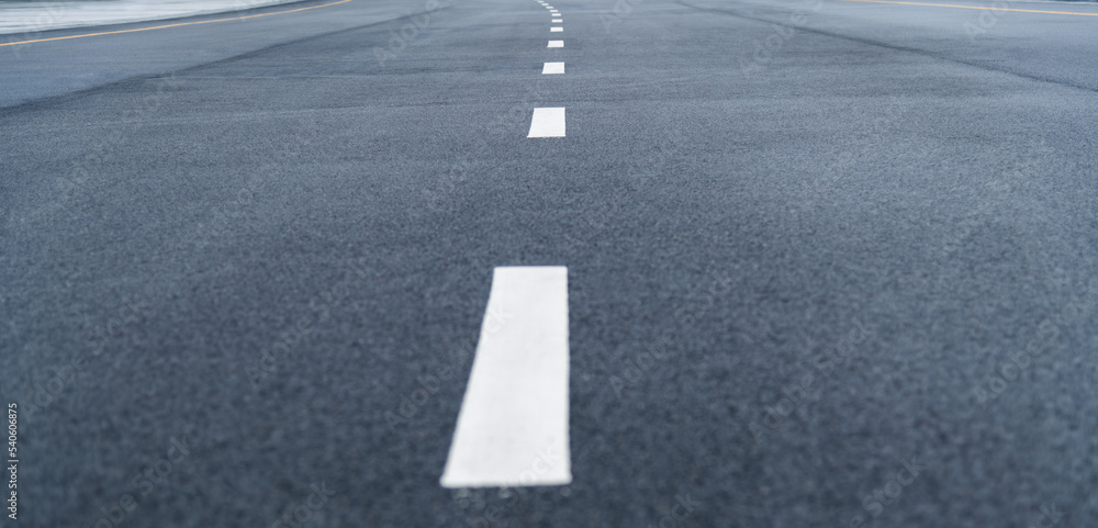 Black asphalt road with white dividing lines