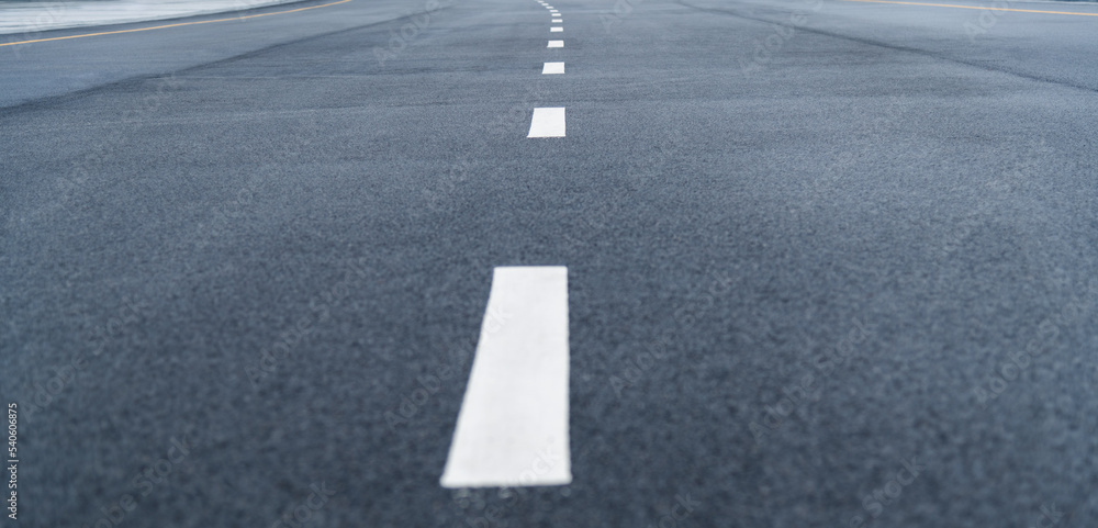 Black asphalt road with white dividing lines Black asphalt road with white dividing lines