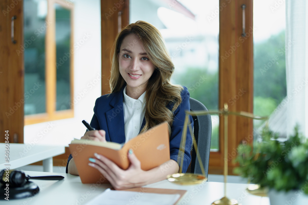 Portrait of a young Asian lawyer studying a lawsuit for a client using notebooks and paperwork on a desk Portrait of a young Asian lawyer studying a lawsuit for a client using notebooks and paperwork on a desk