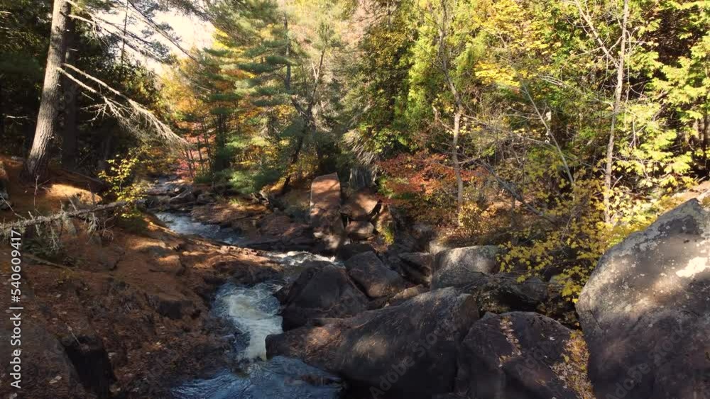Drone flyover River flowing along rocky landscape, surrounded by Dense vegetation, tranquil natural scene Drone flyover River flowing along rocky landscape, surrounded by Dense vegetation, tranquil natural scene