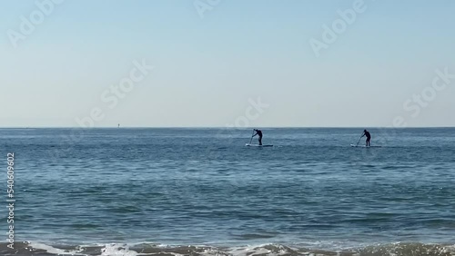 mans paddling on a stand up paddle board in front of the coast of Atlantic ocean. Europe. photo