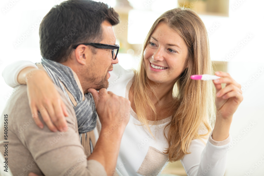 happy couple checking pregnancy test sitting on a couch happy couple checking pregnancy test sitting on a couch
