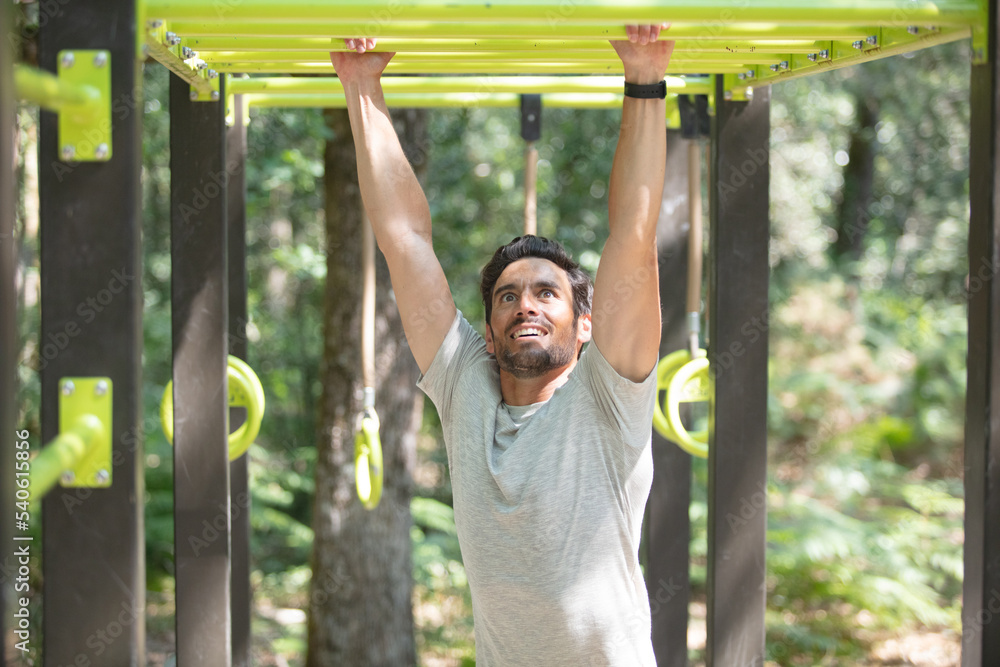 Obraz premium young man doing pull ups on horizontal bar outdoors