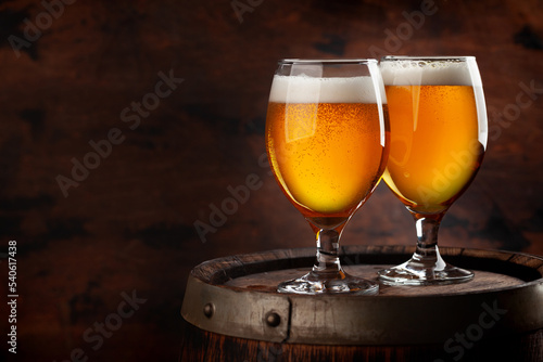 Two beer glasses on wooden barrel