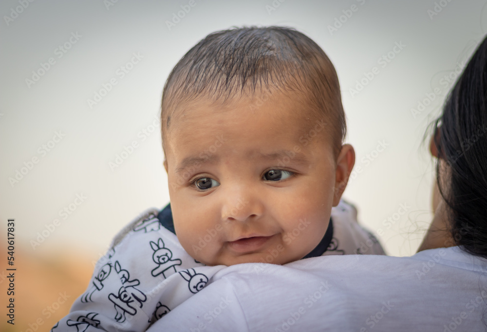 cute infant facial expression resting at mother shoulder from flat angle