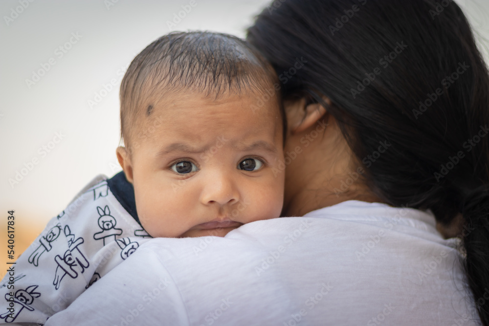 cute infant facial expression resting at mother shoulder from flat angle cute infant facial expression resting at mother shoulder from flat angle