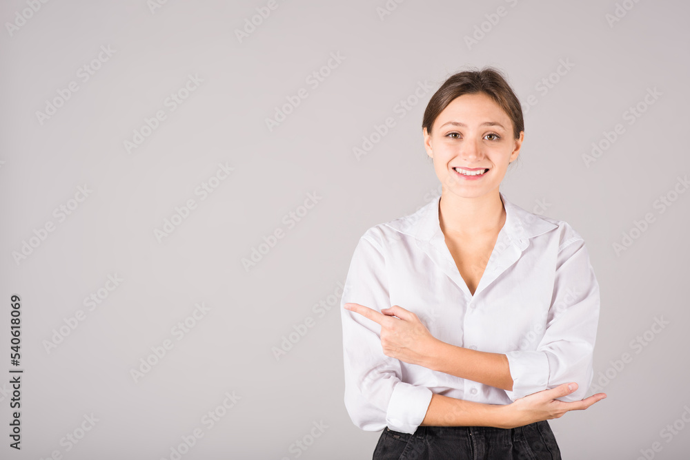 A businesswoman in a white shirt points her finger at a copy space for advertising on a gray background. A businesswoman in a white shirt points her finger at a copy space for advertising on a gray background.