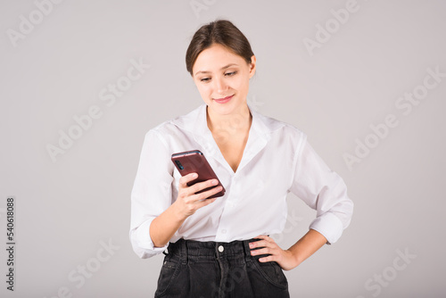 A businesswoman uses a mobile phone on a gray background.