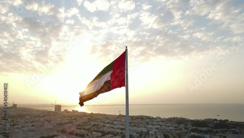 Silhouette: Flag of the United Arab Emirates waving in the air, Sky and Sun Background,  United Arab Emirates. photo